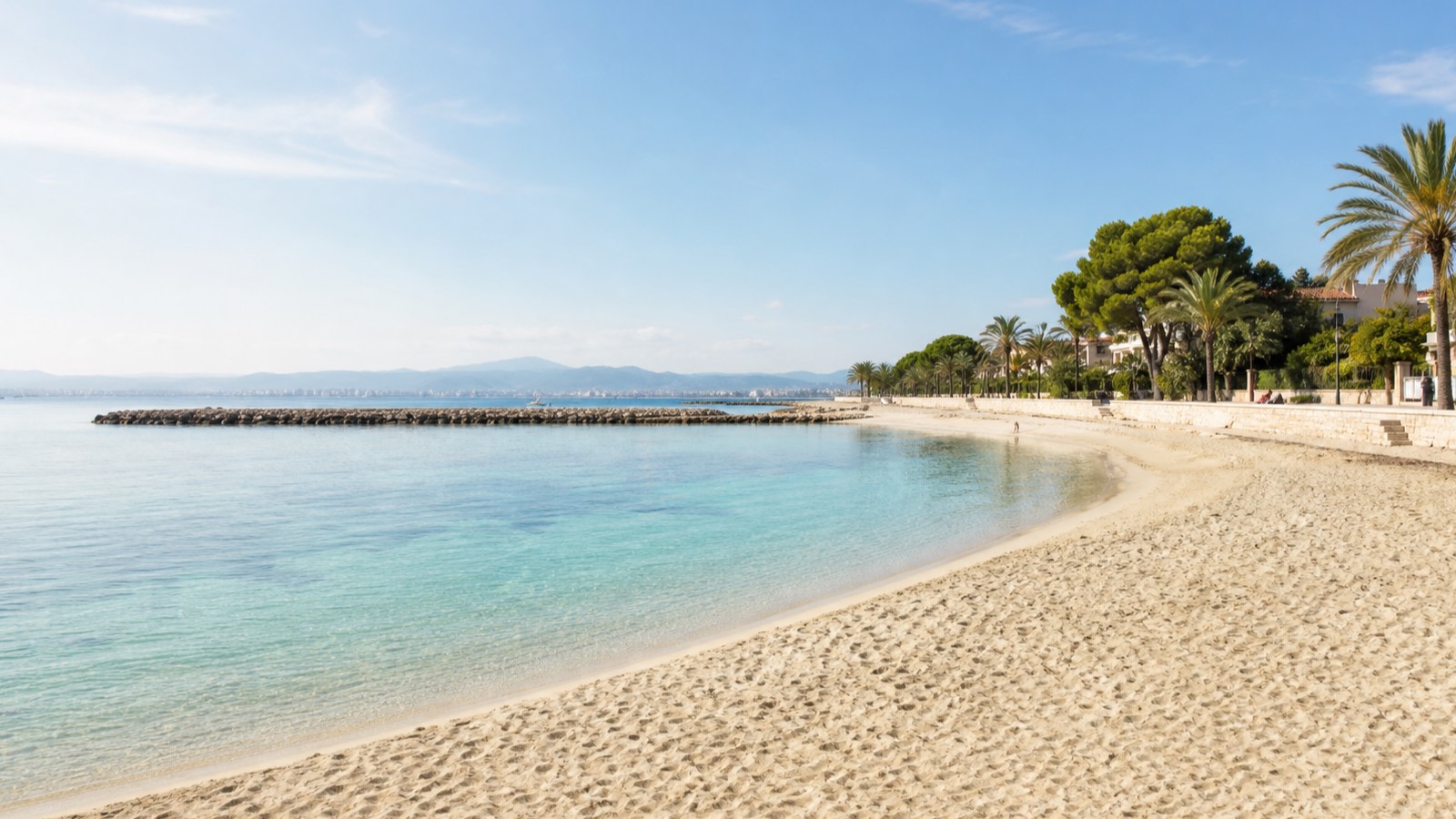 KI-generiertes Stimmungsbild eines geschützten Sandstrands mit ruhigem Wasser, niedrigen Wellenbrechern und grüner Promenade in Ciutat Jardí