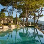 KI-Stimmungsbild für das Four Seasons Resort Mallorca at Formentor mit Infinitypool, Pinien und Blick auf die türkisfarbene Bucht