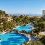 KI-generiertes Stimmungsbild mit großer Poollandschaft, Kinderbecken, mediterranem Garten und Blick zur Bucht für das Grupotel Gran Vista & Spa in Can Picafort