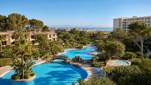 KI-generiertes Stimmungsbild mit großer Poollandschaft, Kinderbecken, mediterranem Garten und Blick zur Bucht für das Grupotel Gran Vista & Spa in Can Picafort