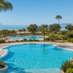KI-Stimmungsbild für Grupotel Marítimo mit zwei Pools, mediterranem Garten und Blick zur Bucht von Alcúdia