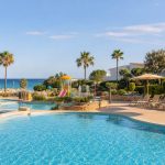 KI-Stimmungsbild für Hipotels Mediterráneo Club mit familienfreundlicher Poollandschaft, Splashbereich und Mittelmeer bei Sa Coma