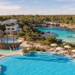 KI-Stimmungsbild für Iberostar Waves Club Cala Barca mit großer Poollandschaft, Kinderbereich und ruhiger Bucht bei Portopetro