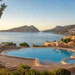 KI-generiertes Stimmungsbild einer terrassierten Poolanlage in Sant Elm mit Blick auf Sa Dragonera für den Universal Aparthotel Don Camilo Hotelcheck