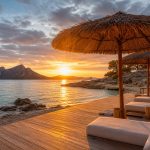 KI-Stimmungsbild für das Universal Hotel Aquamarin mit ruhiger Beach-Club-Terrasse, kleiner Bucht und Blick auf sa Dragonera bei Sonnenuntergang