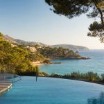 KI-Stimmungsbild für das Universal Hotel Lido Park & Spa mit Außenpool, Pinien, kleiner Bucht und Meerblick bei Peguera
