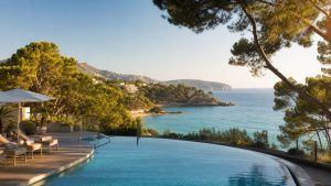 KI-Stimmungsbild für das Universal Hotel Lido Park & Spa mit Außenpool, Pinien, kleiner Bucht und Meerblick bei Peguera